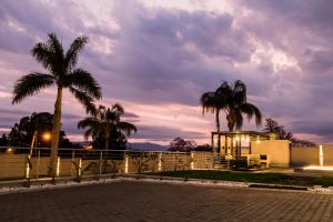 a house with palm trees and a fence at Simphiwe Guesthouse in Manzini