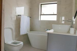 a bathroom with a tub and a toilet and a sink at Simphiwe Guesthouse in Manzini +11 photos