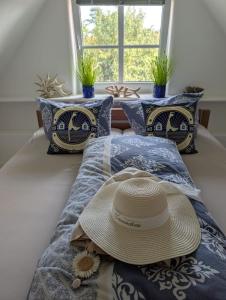 ヴェスターラントにあるPrivates Domizil auf Sylt in Strandnäheの枕と窓のあるベッドの上の帽子