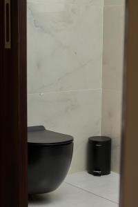 a bathroom with a black toilet and a trash can at Simphiwe Guesthouse in Manzini