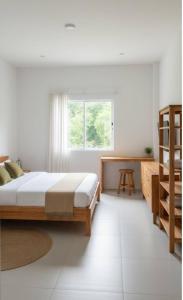 a white bedroom with a bed and a window at Vapanakhaw Ubon in Ubon Ratchathani