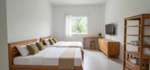 a bedroom with two beds and a television in it at Vapanakhaw Ubon in Ubon Ratchathani
