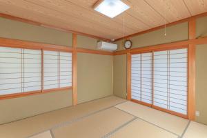 饭田市BANRYU 萬龍 バンリュウ的一间空房间，有三扇窗户和一个钟