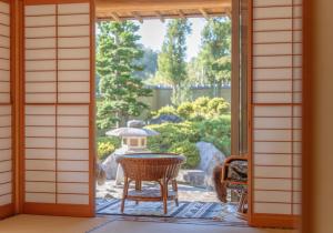 饭田市BANRYU 萬龍 バンリュウ的一扇敞开的门通向露台，露台上摆放着一张桌子和一盏灯笼。