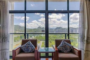 a room with two chairs and a large window at Huangshan Xuanyuan International Hotel in Huangshan
