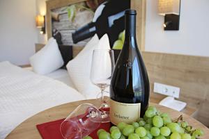Una botella de vino y un montón de uvas en una mesa. en Residence Egger, en Terlano