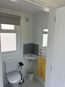 a white bathroom with a toilet and a sink at Luxury Beachfront Lodge in Hest Bank