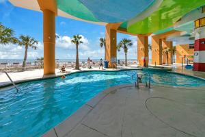 een zwembad in een resort met palmbomen en de oceaan bij Beachfront Condo in Panama City Beach! in Panama City Beach