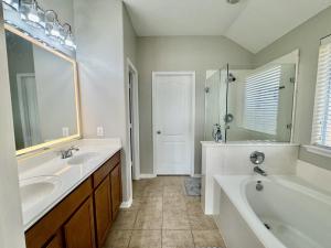a bathroom with two sinks and a bath tub and a tubermott at Katy Getaway - Relaxed 3BR Home with Serene Views in Hoffpauir Airport +18 photos