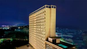 a tall white building at night with a city at HARRIS Hotel & Suites Nagoya Batam in Nagoya