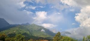 a view of a mountain range with clouds in the sky at Peace Yard in Dharmsāla