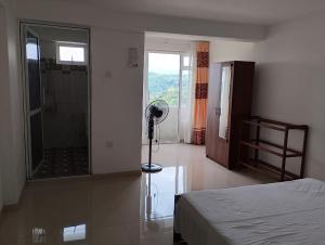 a bedroom with a bed and a shower and a fan at Travelhubs Rooms in Kandy