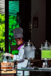 a woman in a kitchen preparing food on a table at The Elements Krabi Resort - SHA Plus in Klong Muang Beach