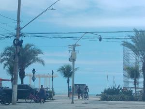 a group of people walking and riding bikes on the beach at Acampamento Aloha solemar in Praia Grande