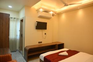 a bedroom with a bed and a tv on the wall at Hotel Rudra in Guwahati