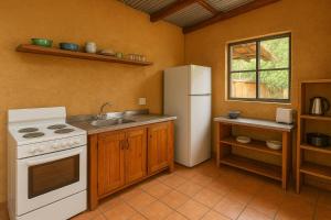 a kitchen with a white stove and a refrigerator at Bushman Spoor Backpackers in Soweto