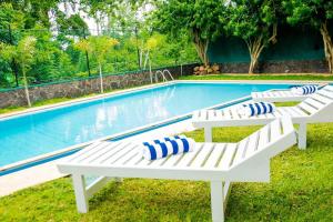 two white benches sitting in front of a swimming pool at Villa TIS in Galle
