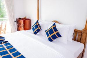 a bedroom with a bed with blue and white pillows at Villa TIS in Galle