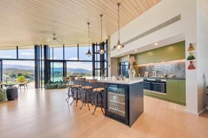 una cocina con armarios verdes y un bar con taburetes en Kaiteri Sands Retreat, en Kaiteriteri