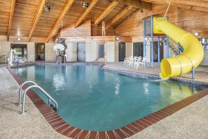 a swimming pool with a yellow slide in a building at AmericInn by Wyndham Chamberlain Conference Center in Chamberlain