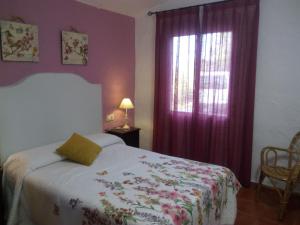 1 dormitorio con 1 cama y una ventana con cortinas moradas en Mirador de Mulera, en Ubrique