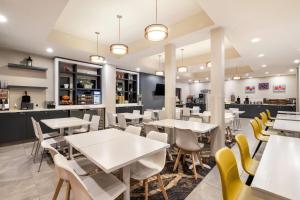 a restaurant with white tables and yellow chairs at Microtel Inn & Suites by Wyndham Mont Tremblant in Mont-Tremblant