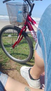Eine Person sitzt neben einem Fahrrad mit Korb in der Unterkunft Acampamento Aloha solemar in Praia Grande