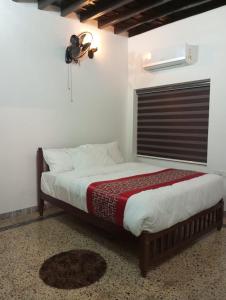 a bedroom with a bed with a fan and a window at Riftha La Banquet in Kannur
