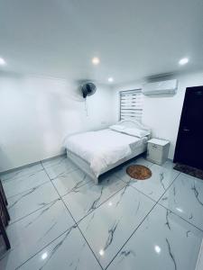 a white bedroom with a bed and a tiled floor at Riftha La Banquet in Kannur
