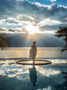 a woman is standing in a fountain by the water at Dali Heartland Castle VILLA Cliffside Sea View Estate in Dali