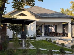 ein Haus mit überdachter Terrasse und Essbereich in der Unterkunft Дачный Дом in Schymkent