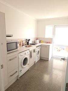 a white kitchen with a sink and washing machines at The Mews - Country Stay in Rolleston