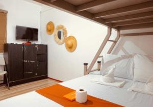 ein Schlafzimmer mit einem weißen Bett und einem Fernseher in der Unterkunft Parasio de Bernal Beach Resort in Cabangan