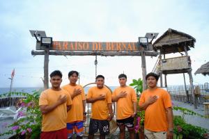 Eine Gruppe Männer in orangefarbenen Hemden steht vor einem Schild. in der Unterkunft Parasio de Bernal Beach Resort in Cabangan
