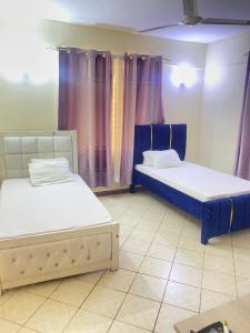 two beds in a room with purple curtains at Amore Cosy 2 Bedroom Apartment in Mombasa