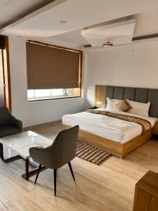 パランプールにあるHotel Postcardのベッドと椅子とテーブルのある寝室