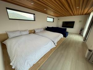 een slaapkamer met een groot bed en een bank bij Kubikai in Itoshima