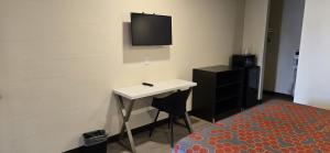 een kamer met een bureau en een tv aan de muur bij Grapevine Inn in Lodi