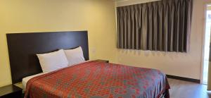 een slaapkamer met een bed met een rood dekbed en een raam bij Grapevine Inn in Lodi