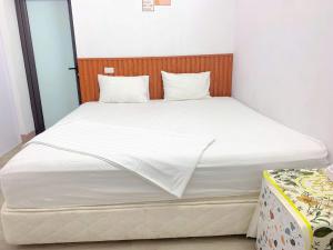 a bed with white sheets and a wooden headboard at Bloom Homestay in Ninh Binh