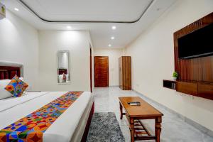 a bedroom with a bed and a table and a tv at FabHotel The Royal Kishan Complex in Noida