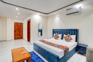 a bedroom with a large bed and a wooden table at FabHotel The Royal Kishan Complex in Noida