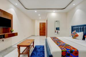 a bedroom with a bed and a table and a tv at FabHotel The Royal Kishan Complex in Noida