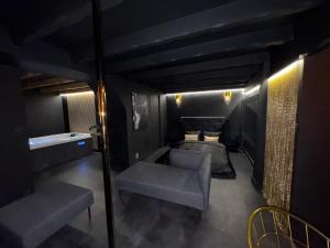 a dark room with a bed and a couch and chairs at SecretRoomBdx in Carbon-Blanc