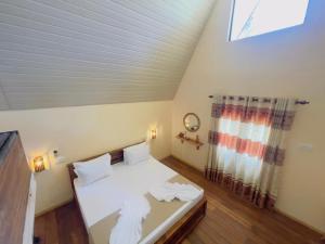 a bedroom with a bed with white sheets and a window at Beach Cabanas Hiriketiya in Hiriketiya