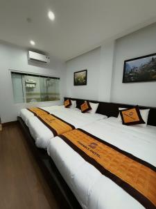 a row of white beds in a room at Friendly Hotel in Dồng Văn