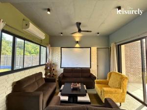 MamnoliStayLeisurely The Flint House 3BHK, Murbad的客厅配有沙发、椅子和屏幕