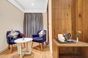 Habitación con 2 sillas azules y mesa. en Hotel Golden Prime Delhi International Airport, en Nueva Delhi