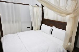 ein Bett mit weißen Laken und Kissen in einem Schlafzimmer in der Unterkunft The Central Spot - Grand Suite in Tirana