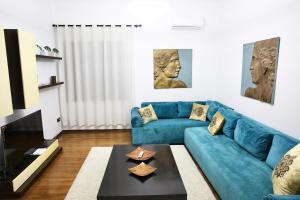 ein Wohnzimmer mit einem blauen Sofa und einem Tisch in der Unterkunft The Central Spot - Grand Suite in Tirana